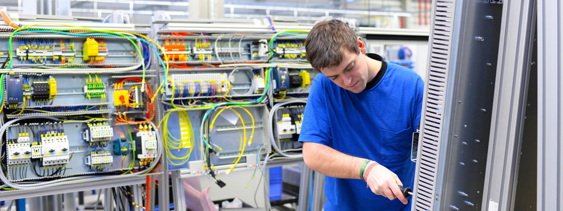 Un employé assemble un panneau de commande électrique - ERP pour la fabrication d'instruments et d'équipements